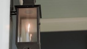 The flickering flame of a vintage style gas lantern mounted to the front porch of a home. - Powered by Shutterstock - Get 15% off with code: PIKWIZARD15