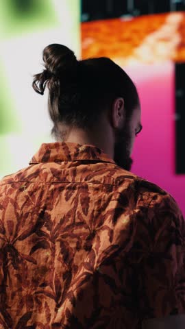 Vertical Video Young carefree man takes selfies and videos surrounded by fun neon lights and beats, representing the fusion of modern DJ culture, media influence and digital art for performance
