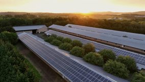 Long barn buildings in American countryside at sunset. Aerial backwards shot. Modern solar panels covering roofs. Green energy theme in rural area of USA. - Powered by Shutterstock - Get 15% off with code: PIKWIZARD15