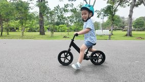 Joyful young Asian Child boy riding balance bike along a path in a park filled with greenery. - Powered by Shutterstock - Get 15% off with code: PIKWIZARD15