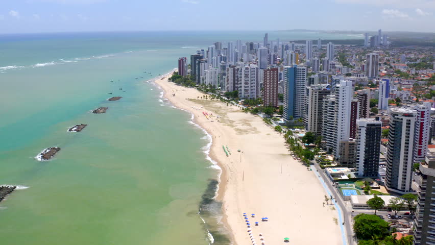 Coastal aerial of Jaboatão dos Guararapes Pernambuco Northeast Brazil displaying the beautiful sea sandy beach clear blue sky city skyline perfect summer vacation image with boat and beach umbrella