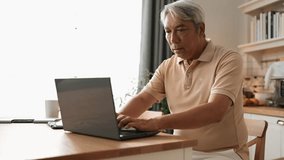 Senior man with casual cloth working on laptop while sitting at home. Elder businessman writing report and looking at financial data while making decision for investment in start up project. Myrmidon. - Powered by Shutterstock - Get 15% off with code: PIKWIZARD15