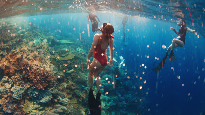 Female freediver swims underwater near the colorfull coral reef in Indonesia and ascends from the depth to the surface