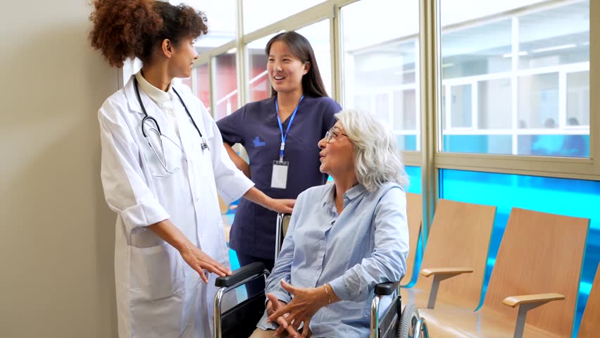 Medical professionals comforting a senior woman in a wheelchair, providing reassurance and care in a hospital waiting area