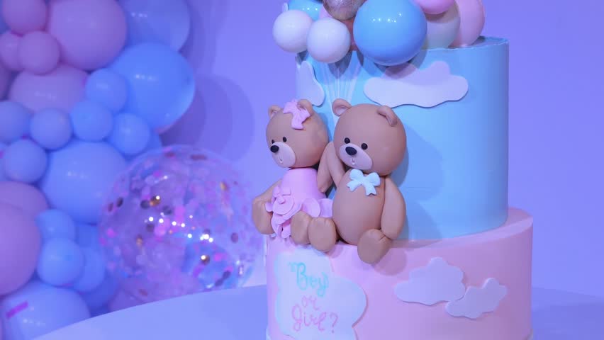 A birthday cake for a gender party with colorful decorations of balloons and a teddy bear. Decor and sweets for a gender party.