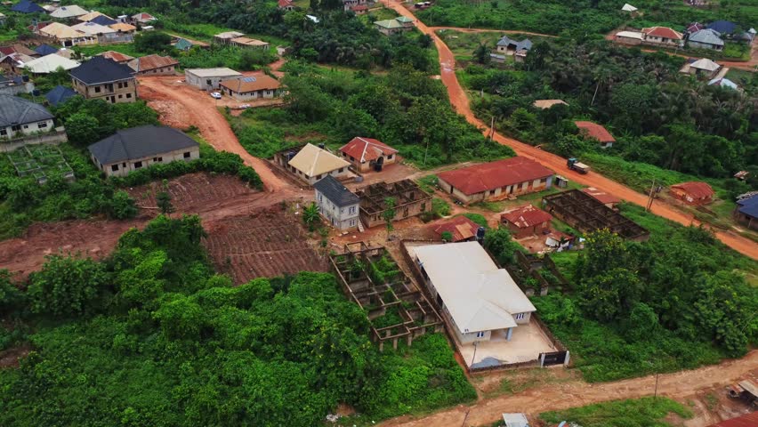 High angle view of homes and partially demolished houses with traffic on a dirt road in rural Nigeria, Africa
