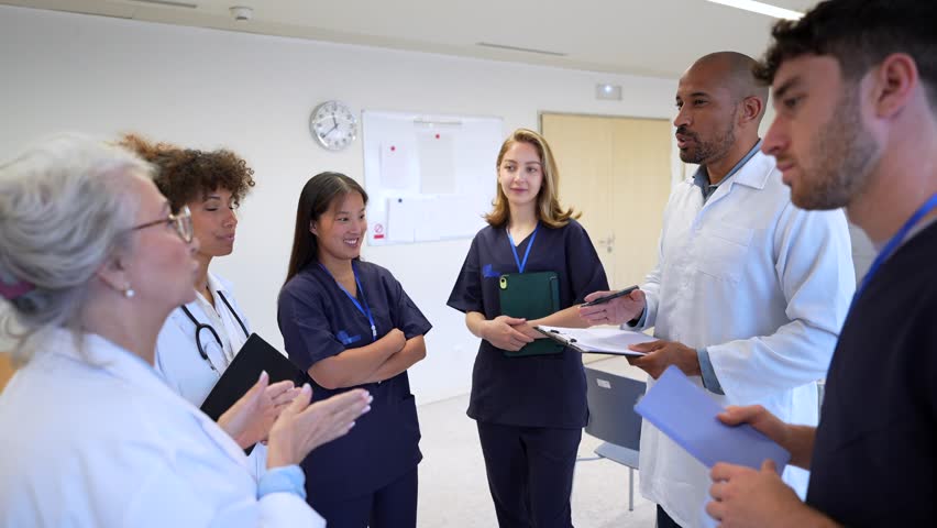 Healthcare professionals discussing patient information while standing in hospital corridor, collaborating and sharing medical insights during team consultation