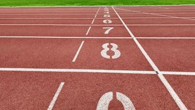 Footage of a red running track with numbered starting lines outdoors. - Powered by Shutterstock - Get 15% off with code: PIKWIZARD15