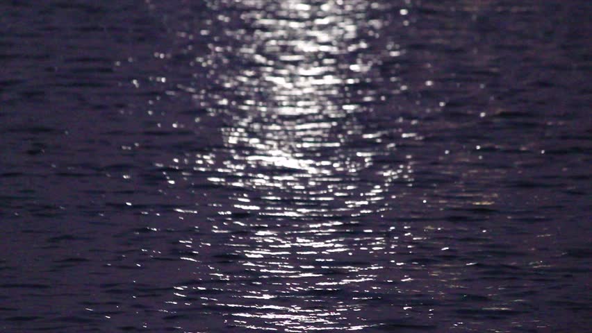 Captivating close-up of water surface at night with shimmering moon or city light reflections. Ideal for calming, mysterious, peaceful and abstract water themes.