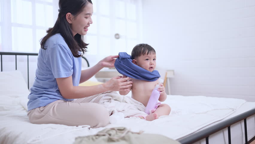 Happy time after bath, Asian kid and mother enjoying are having fun applying cream, powder and dressing up