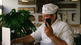 Chef lifting smartphone and typing on laptop, causing network icons multiplying around in tech demo. Digital, connectivity, communication, technology, modern, networking, innovation - Powered by Shutterstock - Get 15% off with code: PIKWIZARD15
