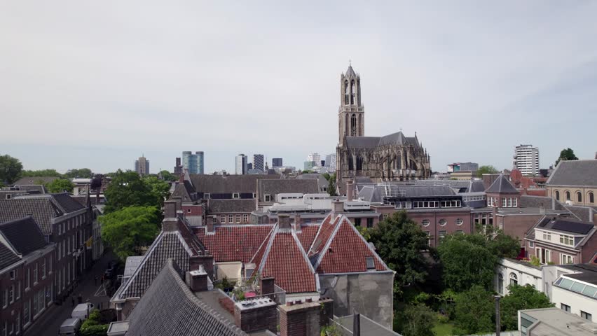 Rooftops of city center with De Dom church tower and the gothic architecture of the Utrecht diocese rising above. Holland religious tourist destination with modern buildings in the background.