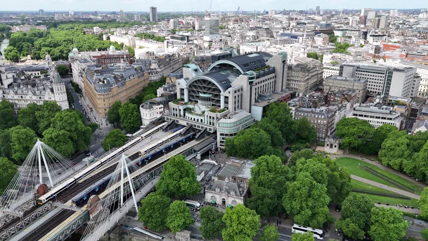 Aerial pan of Charing Cross Station, Victoria Embankment Gardens, and bustling London cityscape. Iconic landmarks and vibrant urban life capture the capital