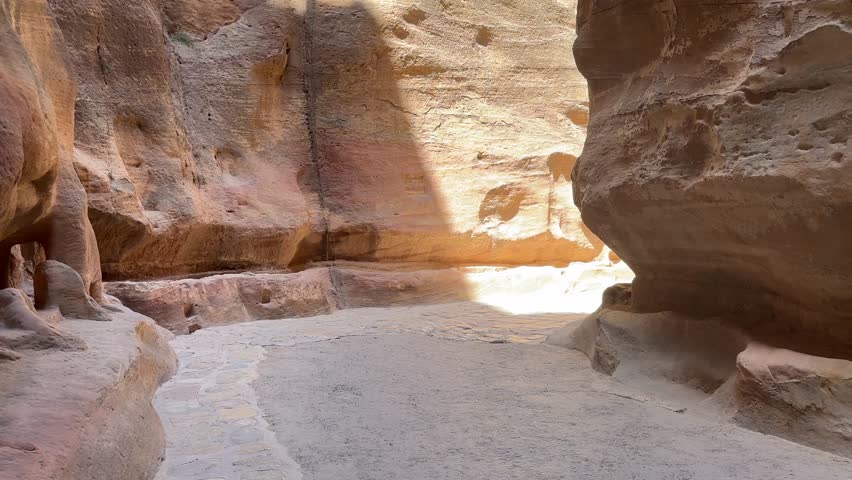 Towering sandstone walls of The Siq pathway leading into the ancient lost city of Petra in Jordan