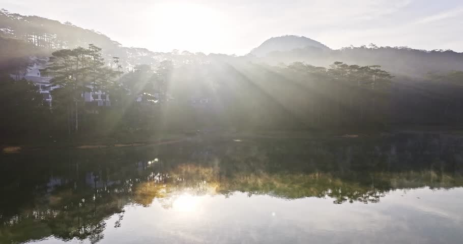 The morning sun rises in the Tuyen Lam lake of ​​Da Lat, Vietnam. The sun shines through the pine hills onto the quiet lake surface, it is wonderful to relax and watch the morning sunrise here.