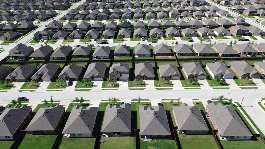 New development residential neighborhood in fast growing urban expansion Dallas Fort Worth metroplex area to surrounding countryside in Princeton, Texas, two story homes with young trees, flyover. USA