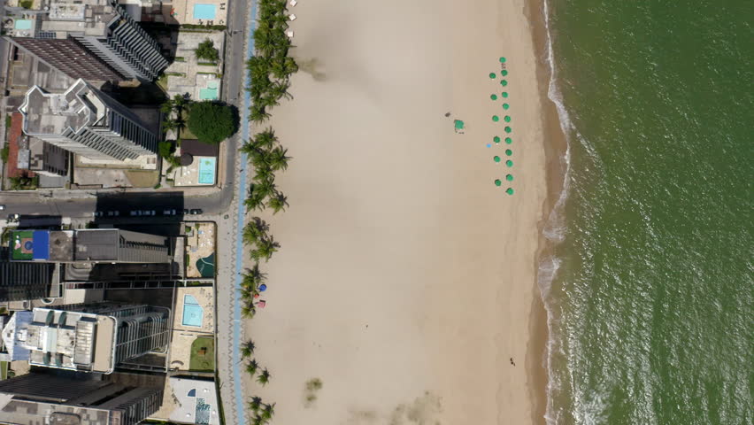 High angle shot of Jaboatão dos Guararapes beachfront Pernambuco Brazil with its distinctive sea white sand clear blue sky coastal buildings perfect for summer holidays featuring a boat and sunshade.