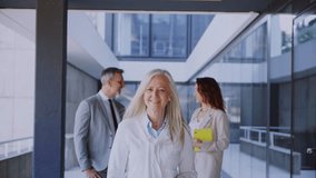 Professional medical team walking confidently through sleek corporate hallway, collaborating with colleagues and displaying expert demeanor in modern workplace setting - Powered by Shutterstock - Get 15% off with code: PIKWIZARD15