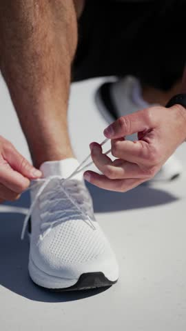Runner prepares for an early morning jog by tying shoelaces at a sunny outdoor location