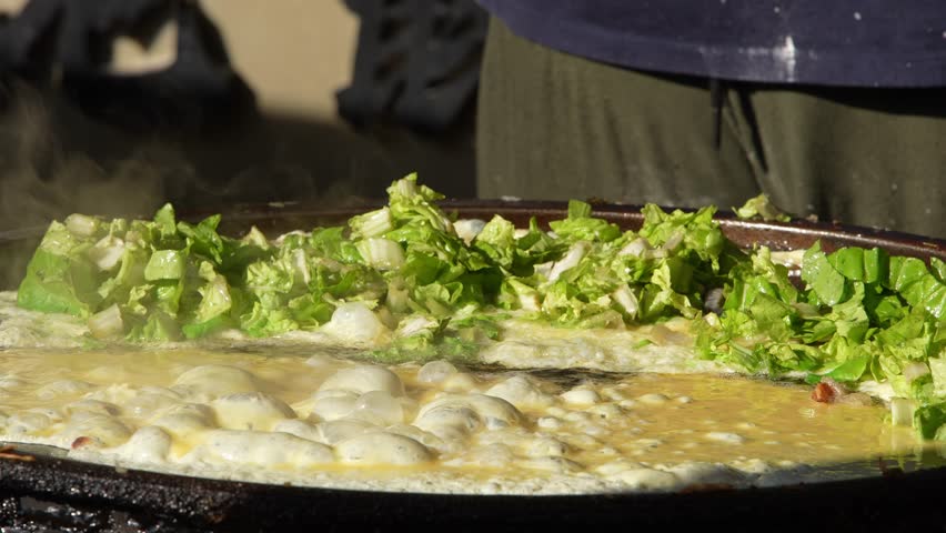 Slow motion of Taiwanese street vendor pouring sauce over freshly cooked oyster omelet at Taichung night market