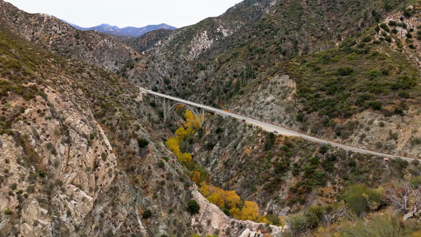 Aerial of Big Tujunga Narrows Bridge along Angeles Forest Highway, Angeles National Forest, California, showcasing vibrant fall foliage and majestic mountain landscapes.
