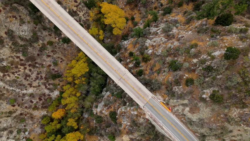 Aerial of Big Tujunga Narrows Bridge along Angeles Forest Highway, Angeles National Forest, California, showcasing vibrant fall foliage and majestic mountain landscapes.