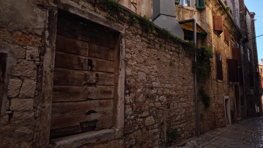 Clothes hanging on a clothesline. Narrow street scenery with beautiful historic residential apartments. Lights and shadows on the street in the old town of Rovinj, Croatia. Looking up.