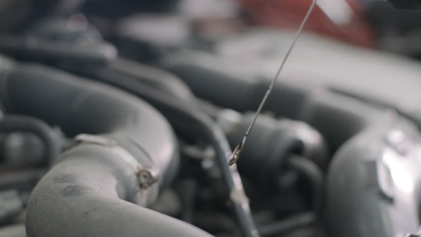 Checking Engine Oil Level with Dipstick in Car Engine Bay
