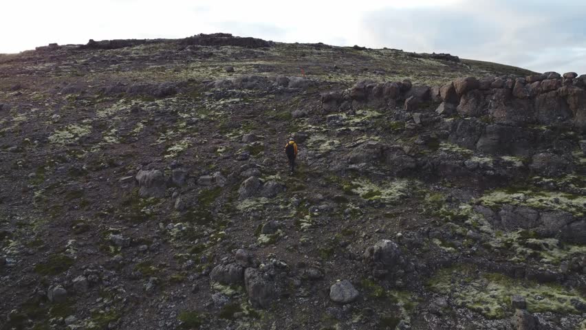 traveler climbs a massive volcanic rock formation at sunset in Grundarfjordur, in western Iceland. 4K video.