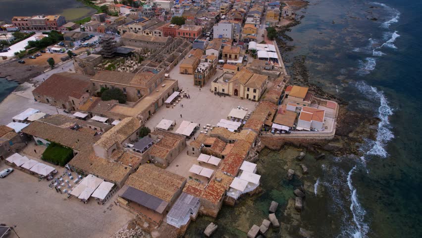 Drone view of Marzamemi, Italy. Charming Sicilian fishing town with boats, old stone houses, and sea