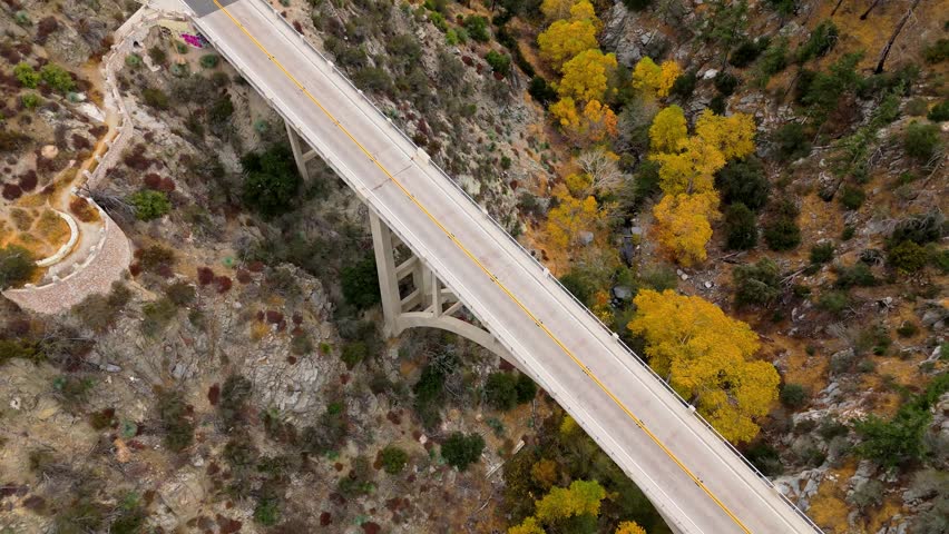 Aerial of Big Tujunga Narrows Bridge along Angeles Forest Highway, Angeles National Forest, California, showcasing vibrant fall foliage and majestic mountain landscapes.