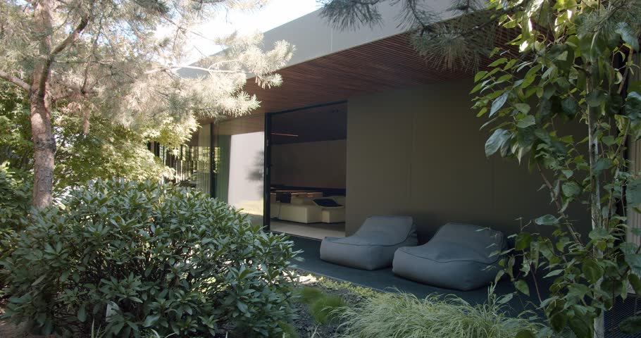 A serene outdoor lounge area seamlessly blending modern architecture with vibrant natural elements and sleek furniture. Modern Outdoor Living Space with Lush Greenery and Comfortable Seating
