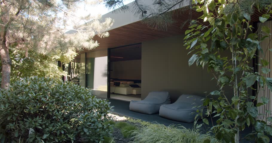 A serene outdoor lounge area seamlessly blending modern architecture with vibrant natural elements and sleek furniture. Modern Outdoor Living Space with Lush Greenery and Comfortable Seating