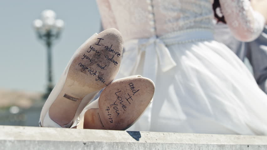 Unique wedding shoes signed by bride and groom displayed outdoors