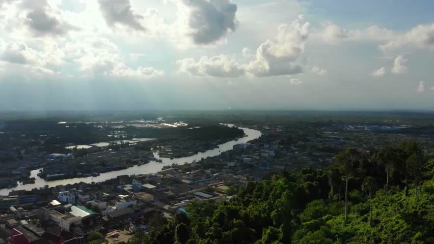 Aerial View of River Winding Through Cityscape Under Cloudy Sky