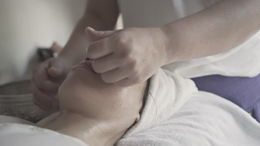 A woman is getting a facial treatment. The woman is smiling and relaxed