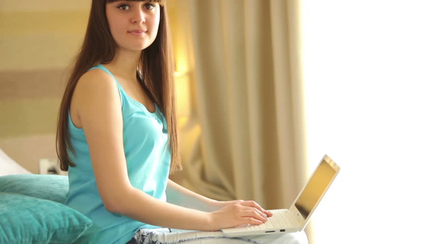 Young woman with laptop looking at camera and laughing

