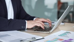 Close up of male hands typing on laptop keyboard in modern office. Asian businessman works on a computer sitting at a workplace at a desk. Concept of technology use, and professional work environment - Powered by Shutterstock - Get 15% off with code: PIKWIZARD15