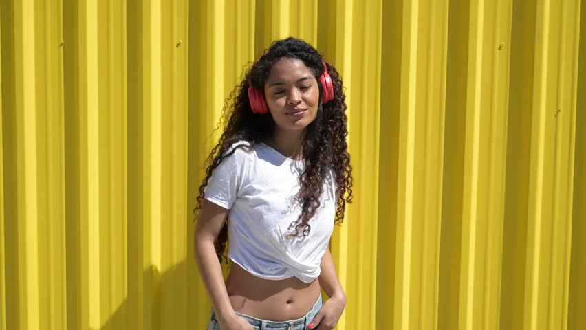 Young woman dancing and listening to music with red headphones