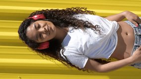 Young woman listening music with red headphones and dancing.Vertical video - Powered by Shutterstock - Get 15% off with code: PIKWIZARD15