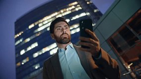 Confident director using smartphone standing evening light architecture closeup. Smiling businessman looking mobile phone reading email in night commercial district. Elegant business owner after work - Powered by Shutterstock - Get 15% off with code: PIKWIZARD15