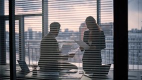Manager silhouette talking executive at panorama window cabinet. Unrecognized finance analysts checking reading report papers at dark room. Anonymous subordinate woman assisting boss in cityscape  - Powered by Shutterstock - Get 15% off with code: PIKWIZARD15