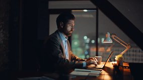 Late worker typing computer taking coffee sip sitting office desk closeup. Bearded confident corporate employee looking screen flipping documents at workplace. Serious businessman doing laptop work  - Powered by Shutterstock - Get 15% off with code: PIKWIZARD15