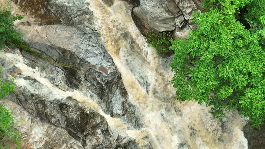 Drone view of a flooded river rushing through dense rainforest, highlighting vital ecosystems that support biodiversity, carbon capture, and climate resilience. Thailand.
