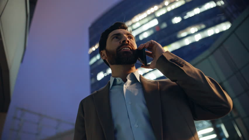 Overjoyed company owner calling smartphone on evening street closeup. Happy businessman talking cellphone rejoicing success feeling excited. Emotional joyful manager sharing great news by mobile phone