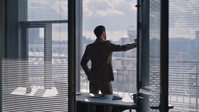Corporate leader watching skyline reflecting ambitions during day moment. Thoughtful executive wearing formal clothes gazing outside glass facade. Worried sad worker considering decision in workplace - Powered by Shutterstock - Get 15% off with code: PIKWIZARD15