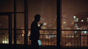 Concerned lawyer silhouette talking mobile phone crossing at evening panoramic cabinet alone. Worried businessman discussing work in tensed cellphone call indoor. Nervous ceo speaking cell emotionally - Powered by Shutterstock - Get 15% off with code: PIKWIZARD15