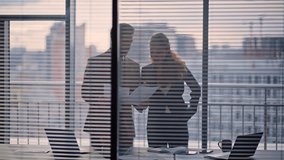 Couple businesspeople doing paperwork standing at panoramic office. Busy colleagues analyzing contract papers at grey cityscape. Businessman businesswoman silhouettes work together at private room - Powered by Shutterstock - Get 15% off with code: PIKWIZARD15