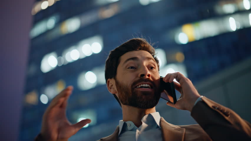 Delighted entrepreneur speaking mobile device standing downtown at dusk portrait. Cheerful executive receiving positive update expressing happiness. Ecstatic boss enjoying achievement in phone call