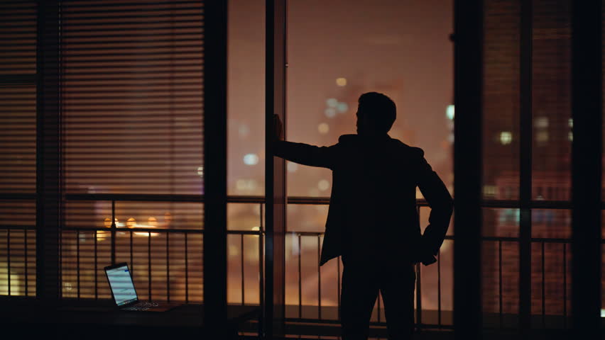 Troubled professional silhouette thinking problem at cityscape panoramic office back view. Company man in suit looking window pondering problem alone. Worried manager feeling nervous at dark workplace